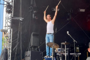 Schlagzeuger Bastian steht auf der basedrum und hält die Sticks nach oben